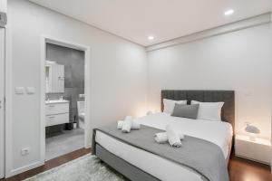 a white bedroom with a large bed and a bathroom at Libertà Lodge Apartment - Minho's Guest in Braga
