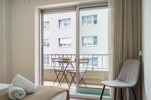 a bedroom with a bed and a balcony with a table and chair at Libertà Lodge Apartment - Minho's Guest in Braga