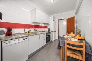 a kitchen with white cabinets and a table with fruit on it at Apartamento 3 Nações in Alvor