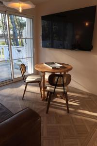 a table and two chairs in a room with a television at VANILLA Lodge in Lacanau-Océan