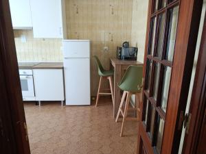a kitchen with a white refrigerator and a table and chairs at A Ribeira in Fene +16 photos