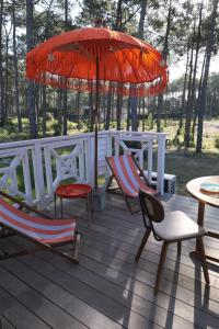 a deck with chairs and an umbrella and a table at VANILLA Lodge in Lacanau-Océan