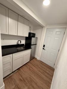 a kitchen with white cabinets and a sink and a door at Suite Safari in Tampa