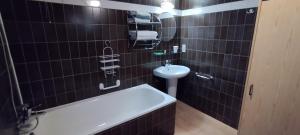 a black tiled bathroom with a sink and a bath tub at L'Horizon Studios & Apparts in Malmedy +57 photos