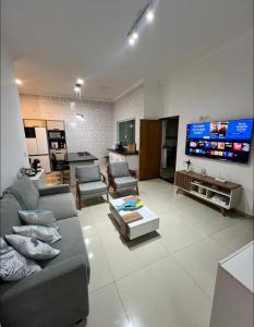a living room with a couch and a tv at Piscina Aquecida Quartos com Ar cond 700m Praia in Peruíbe
