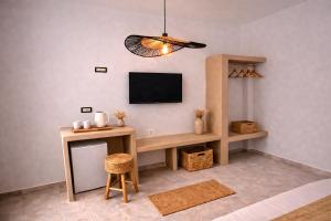 a living room with a tv and a table with a stool at Noème Santorini in Perissa