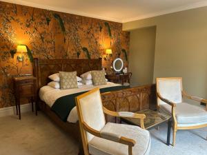 a bedroom with a bed and two chairs and a mirror at Baytree House in Harrogate