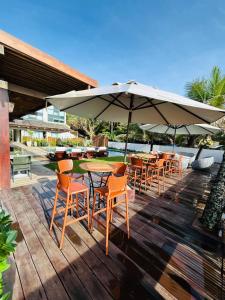 a patio with tables and chairs and an umbrella at Pousada de Charme Refugio da Villa - Pé na Areia in Porto De Galinhas