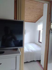 a flat screen tv in a bedroom with a bed at The red cottage in Kumlinge in Kumlinge