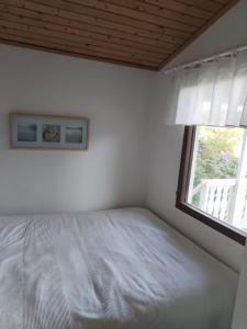 a white bedroom with a bed and a window at The red cottage in Kumlinge in Kumlinge