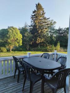 a black table and chairs on a deck with a tree at The red cottage in Kumlinge in Kumlinge