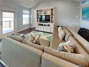 a living room with a large couch and a television at Beachfront Blue in Galveston