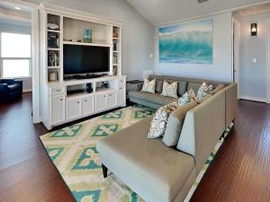 a living room with a couch and a television at Beachfront Blue in Galveston