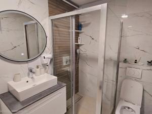 a white bathroom with a sink and a shower at Sarajevo Central View Apartment in Sarajevo +4 photos