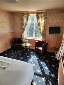 a hotel room with a bed and chairs and a tv at The Limes Hotel in Market Rasen