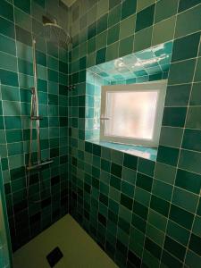 a green tiled bathroom with a window and a shower at Native Surfhouse in Praia da Areia Branca +48 photos