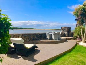 a deck with a table and chairs and a view of the water at The Beach Barn in Cardiff