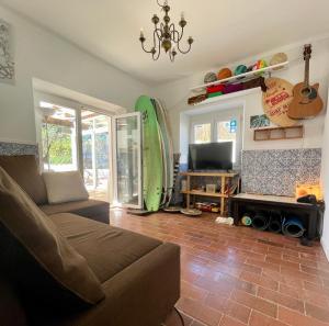 a living room with a couch and a surfboard at Native Surfhouse in Praia da Areia Branca