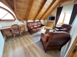a living room with leather furniture and a wooden ceiling at Vila Banga in Nida