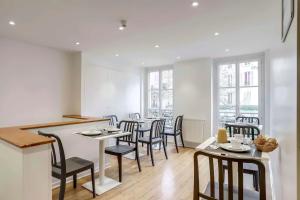 a dining room with tables and chairs and windows at Hotel Royal Mansart in Paris