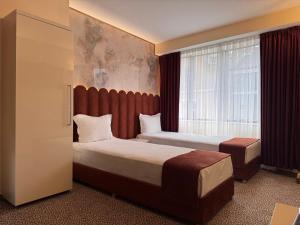 ein Hotelzimmer mit zwei Betten und einem Fenster in der Unterkunft Hotel Dafi in Plowdiw