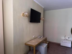 ein Zimmer mit einem Tisch und einem Fernseher an der Wand in der Unterkunft Hotel Dafi in Plowdiw
