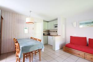 a kitchen and dining room with a table and a red couch at Swing Moliets - T2 bis - Golf - 3 Piscines - Plage in Moliets-et-Maa