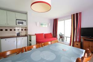 a living room with a red couch and a kitchen at Swing Moliets - T2 bis - Golf - 3 Piscines - Plage in Moliets-et-Maa