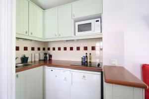 a kitchen with white cabinets and a microwave at Swing Moliets - T2 bis - Golf - 3 Piscines - Plage in Moliets-et-Maa
