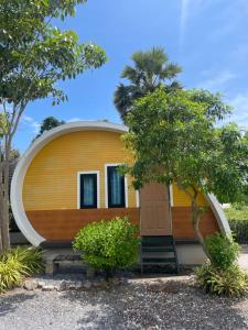 a circular house with a yellow and white facade at Hun Resort in Khanom