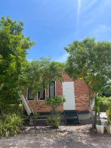 a brick house with a white door and trees at Hun Resort in Khanom +2 photos
