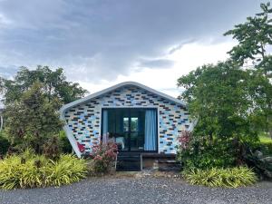 a small house with a front door in a garden at Hun Resort in Khanom