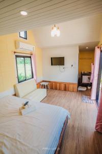 a room with a bed and a couch and a television at Hun Resort in Khanom
