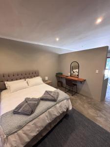 a bedroom with a bed and a desk with a mirror at LuVic Guesthouse in Naboomspruit