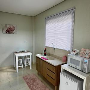 a kitchen with a sink and a microwave at Chalé Rosa - Top Country Ranch in Boituva