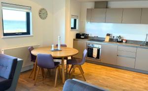 a kitchen with a wooden table and a table and chairs at Findochty - 2 Bed Luxury Apartment by Together Travel in Wick