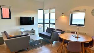 a living room with a table and chairs and a television at Findochty - 2 Bed Luxury Apartment by Together Travel in Wick +7 photos