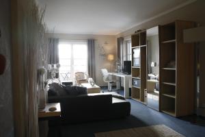 a living room with a couch and a desk and a window at Seehof Hotel am Aartalsee in Bischoffen