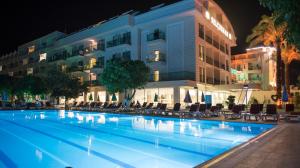 a swimming pool in front of a hotel at night at Selcukhan Hotel in Beldibi