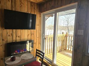 ein Zimmer mit Tisch, Fernseher und Balkon in der Unterkunft Parc Octopus in Desbiens