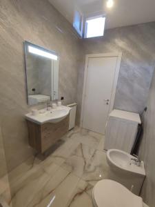 a bathroom with a sink and a toilet and a mirror at Casa Mare Relax e Cortesia in Ardea