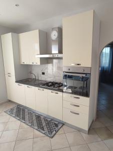 a kitchen with white cabinets and a stove at Casa Mare Relax e Cortesia in Ardea