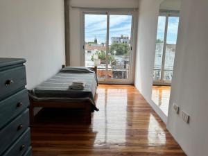 a bed in a room with a large window at DEPARTAMENTO dos dormitorios en Martinez, cercano a CABA, zona clinicas y oficinas, con AA y Wifi, ideal familias in Martínez