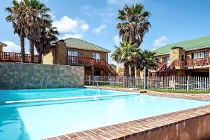 a swimming pool in front of a house with palm trees at Shearwater Studio Sedgefield in Sedgefield