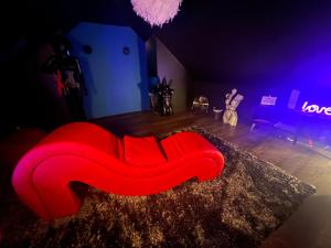 a red couch sitting on the floor in a room at LoveRoom avec SPA privatif Plélo in Plélo