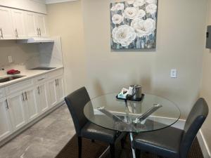 a kitchen with a glass table and two chairs at Arbutus Inn in Victoria