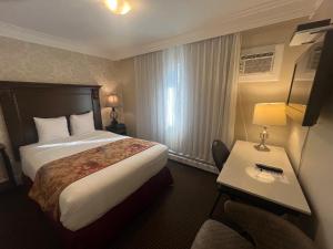 a hotel room with a large bed and a table at Arbutus Inn in Victoria