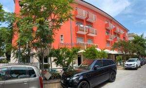 a black car parked in front of a red building at Hotel Aron Rimini in Rimini