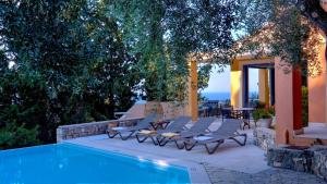 a swimming pool with chairs and a table next to a house at Villa Pelagos in Arvanitakaíïka