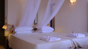 two beds in a room with white sheets and towels at Villa Pelagos in Arvanitakaíïka